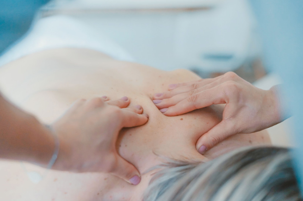 Mainile unui terapeut care face masaj pe spatele unei femei
