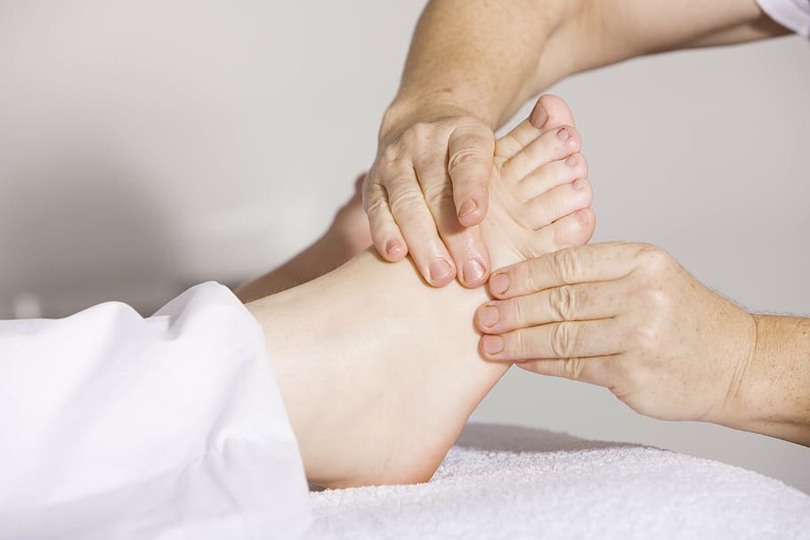 Mainile unui terapeut care executa un masaj reflexogen la piciorul pacientului