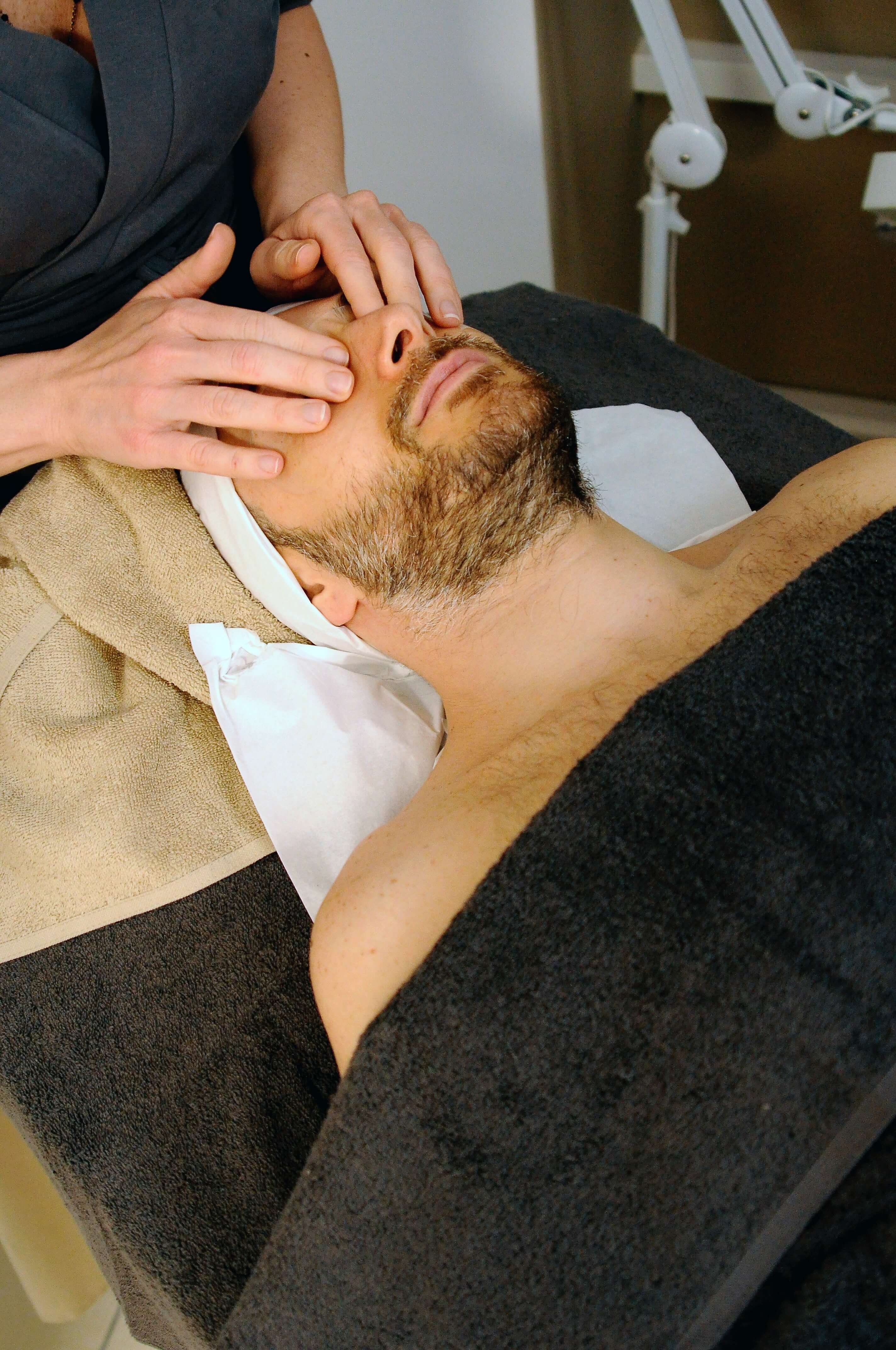 Barbat la salonul de cosmetica in timpul unui masaj facial