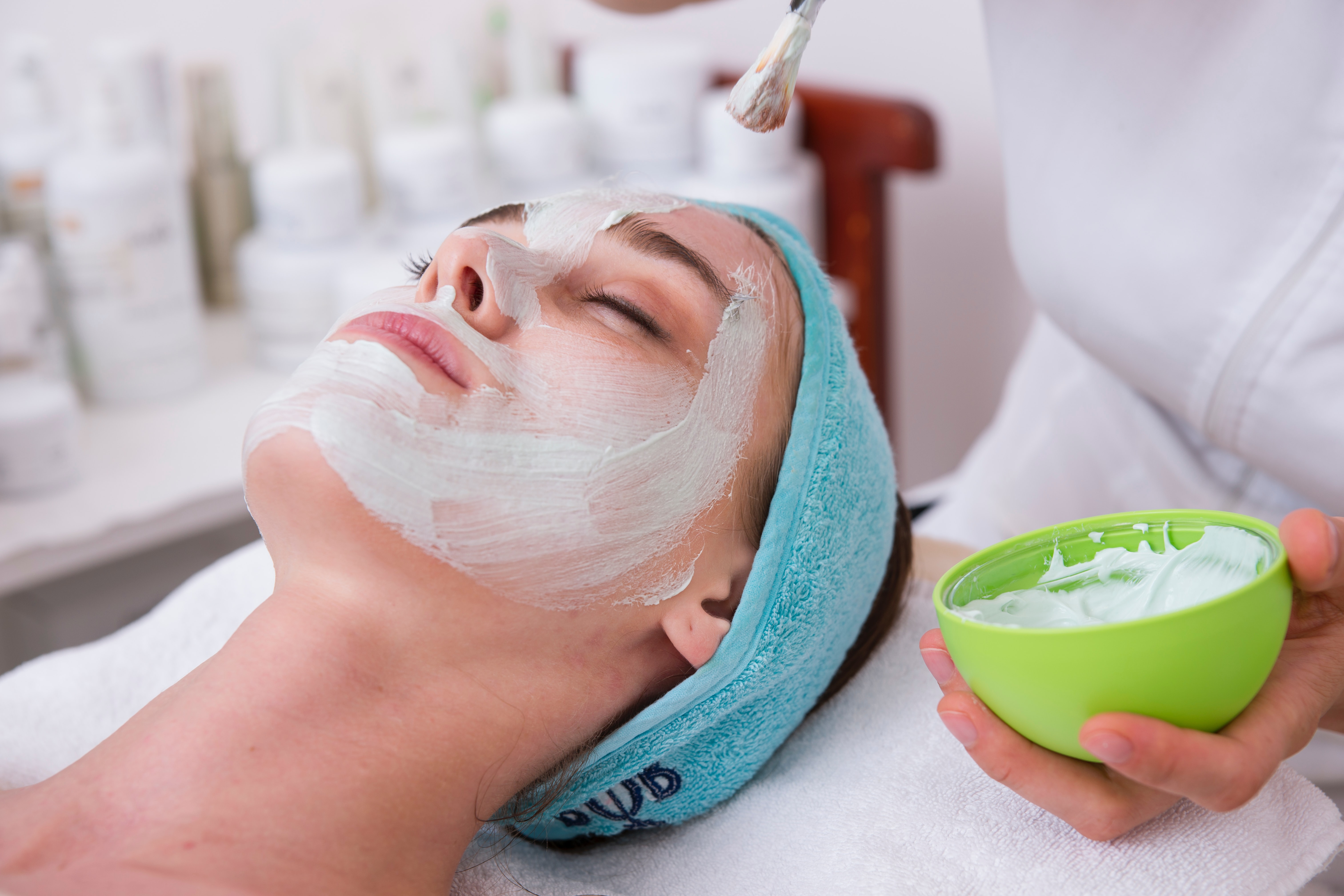 Femeie la salonul de cosmetica in timp ce i se aplica o masca faciala