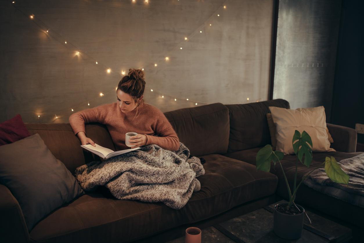 Femeie citind relaxată pe o canapea într-un interior de sufragerie