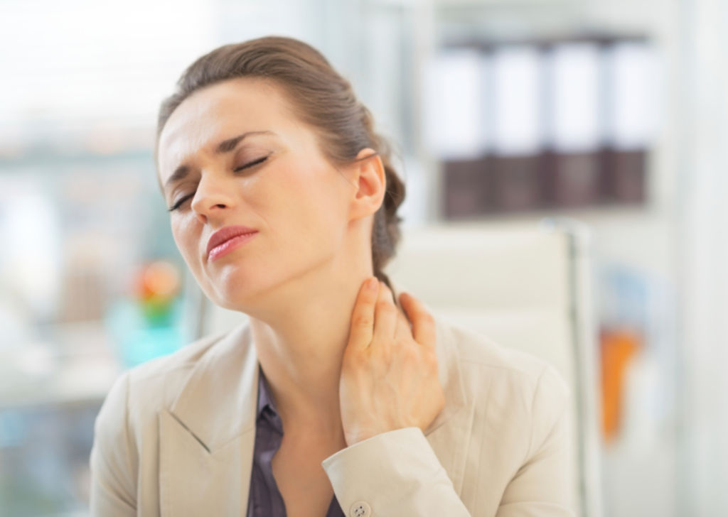 Femeie acuzând dureri cervicale în timpul muncii la birou