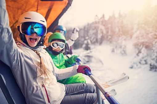 Copii echipați pentru schi, fericiți într-un telescaun la munte