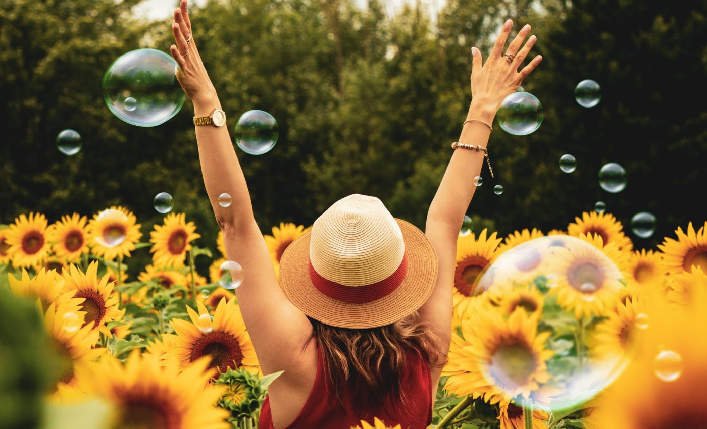 Femeie într-un lan de floarea soarelui într-o atitudine fericită