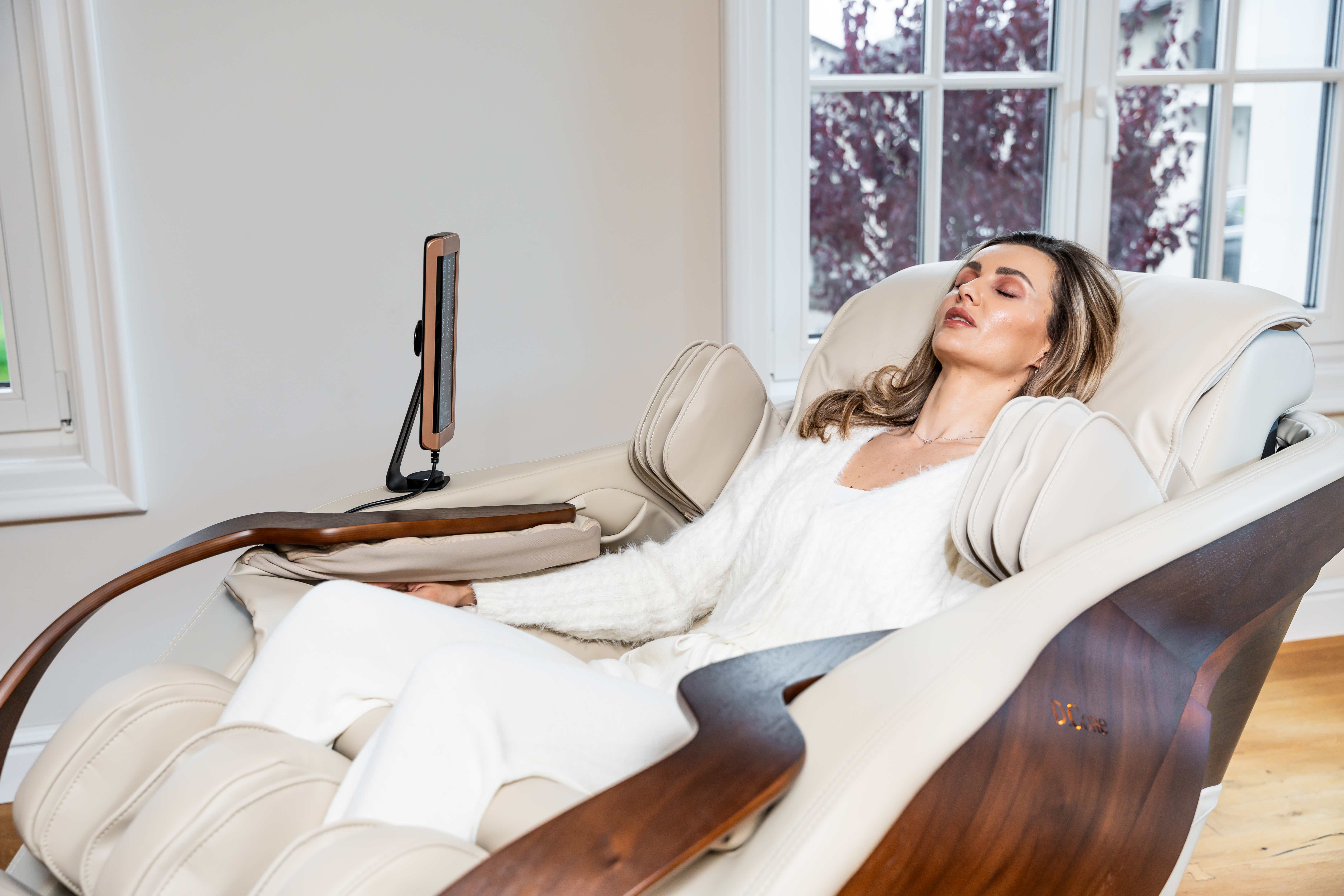 Fotoliu de masaj Cirrus beige, de la Komoder, cu un model feminin într-un interior domestic.